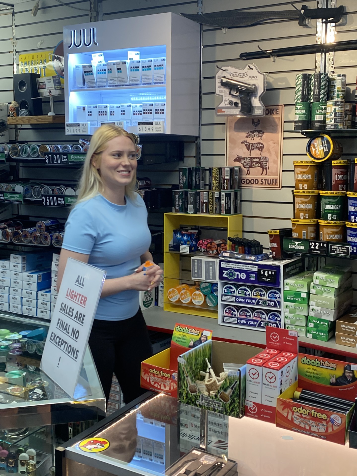 Cashier at the Frontier Tobacco register with JUUL case behind